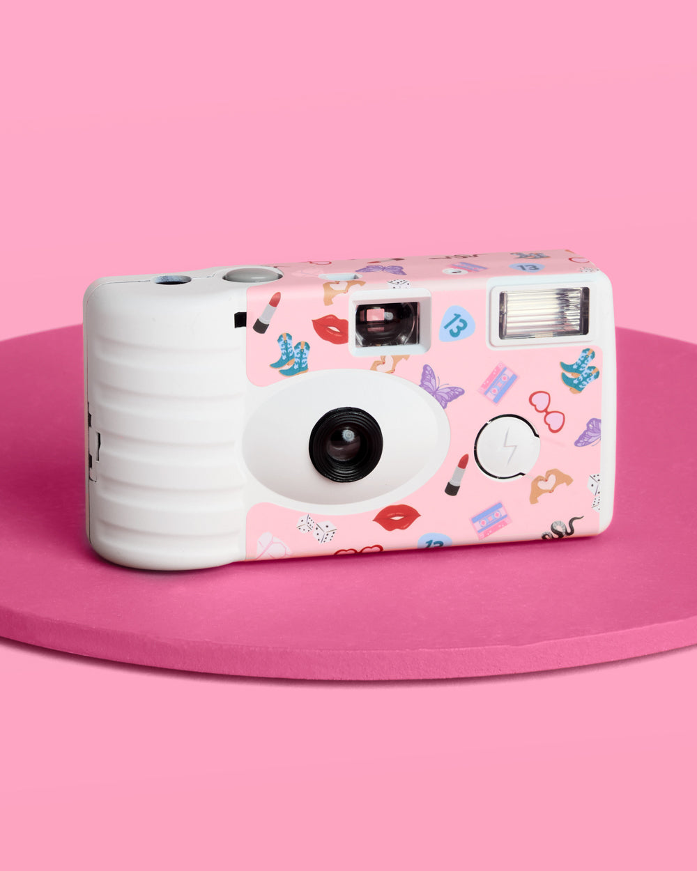 Pink and white camera with colorful designs on a pink background