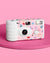 Pink and white camera with colorful designs on a pink background