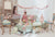 Two young girls in a decorated room with a tea party setup, including a table with teacups and a cart with pastel decorations.