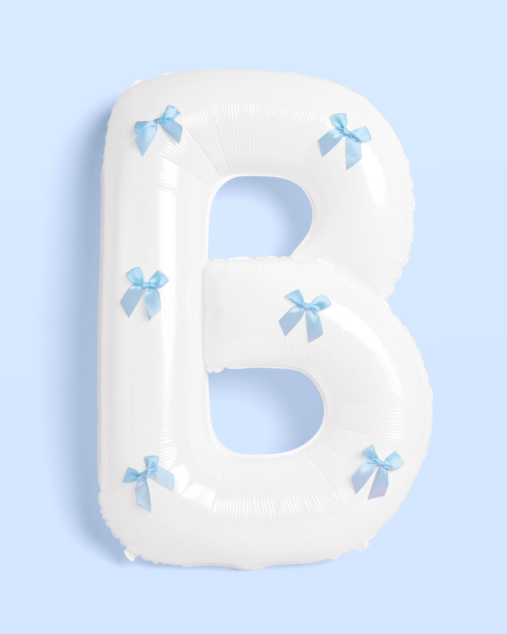 Letter 'B' pillow with blue bows on a light blue background