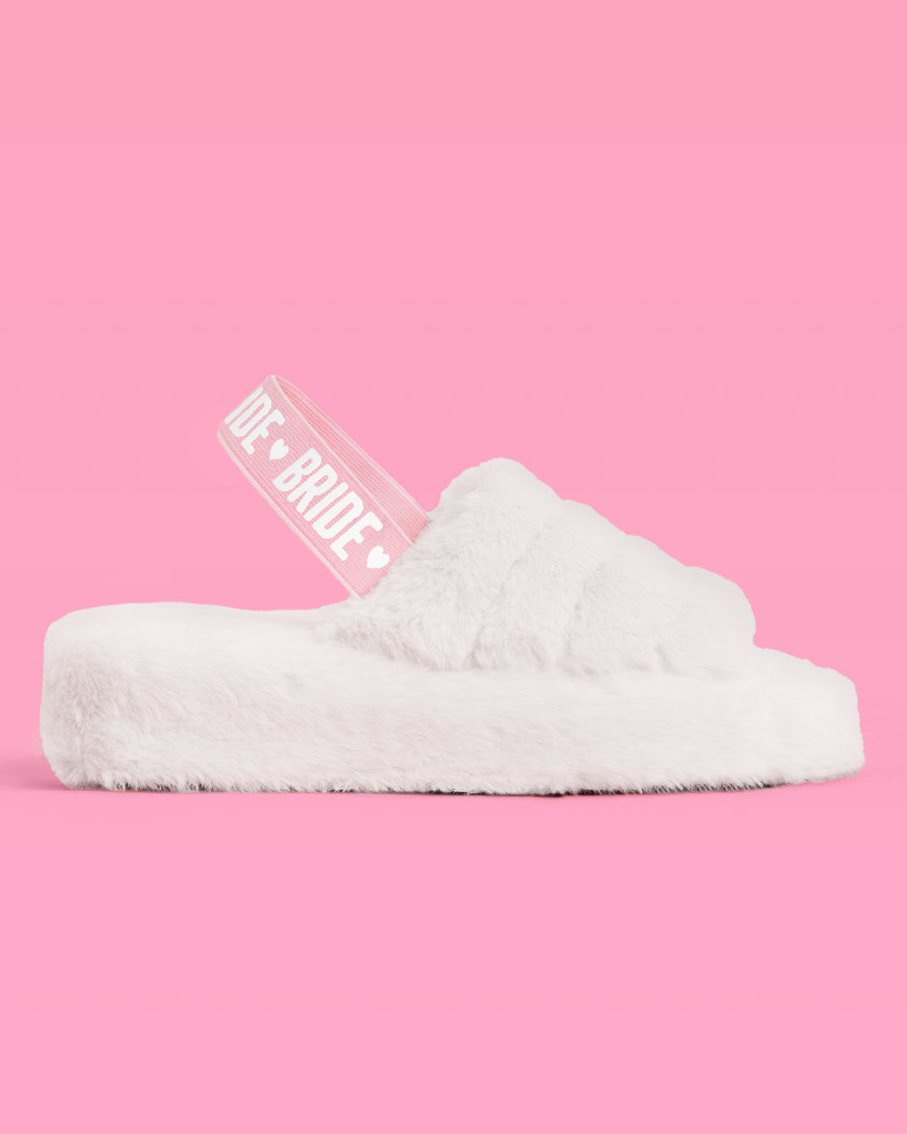 White fuzzy slide sandal with 'Bride' text on a pink background