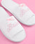White slippers with 'Bride' embroidery on a pink background