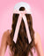 Woman wearing a white cap with a pink ribbon on a pink background