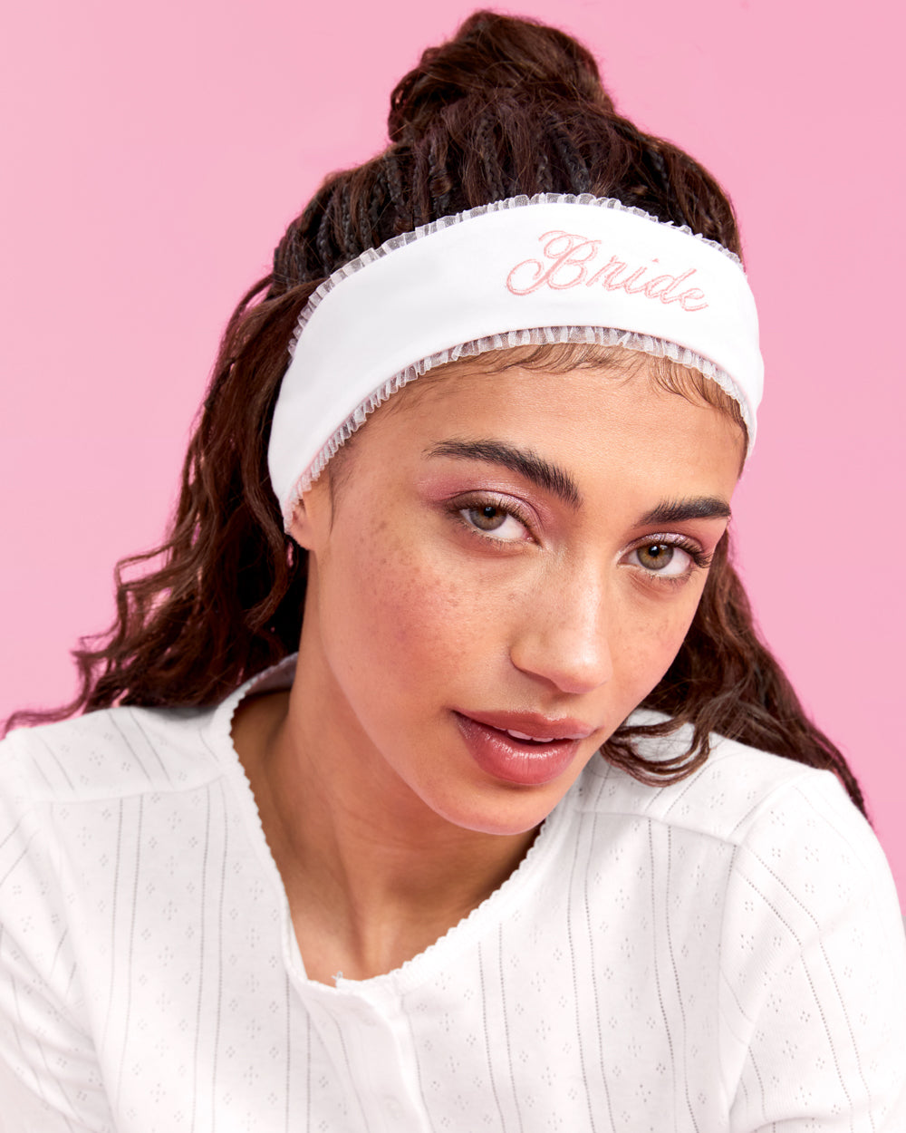 Woman wearing a white headband with 'Bride' text against a pink background