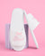 White slippers with 'Bride' text and pink bows on a pink background