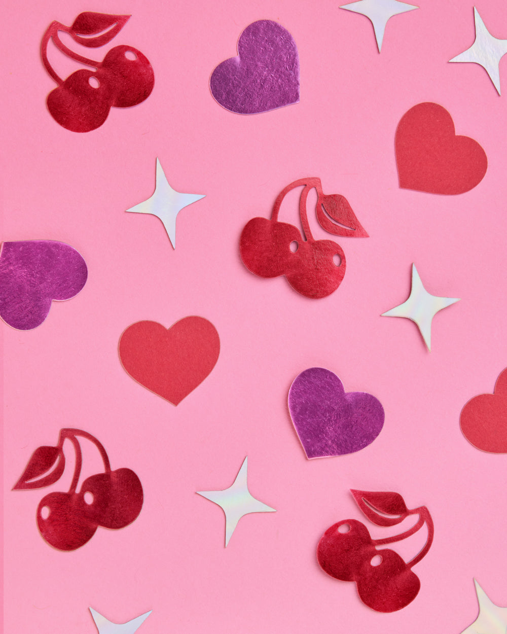 Pattern of red cherries, purple hearts, and white stars on a pink background