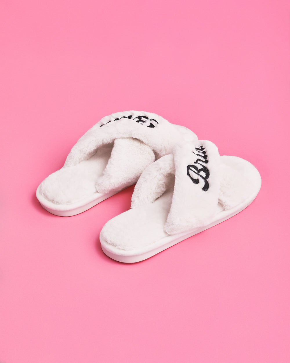 White slippers with &#39;Bride&#39; text on a pink background