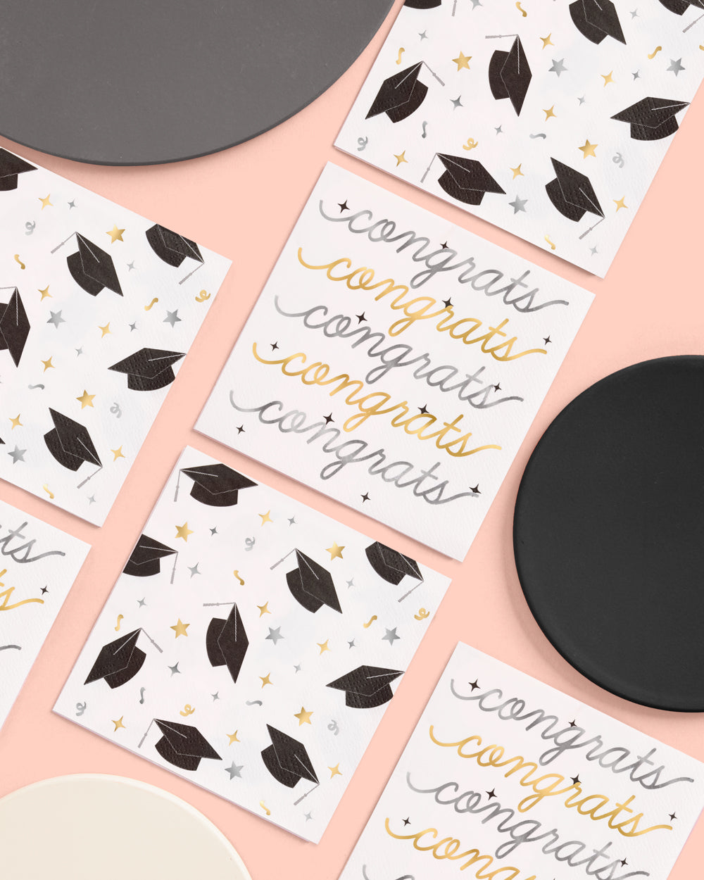 Graduation-themed coasters with &#39;congrats&#39; text on a pink surface