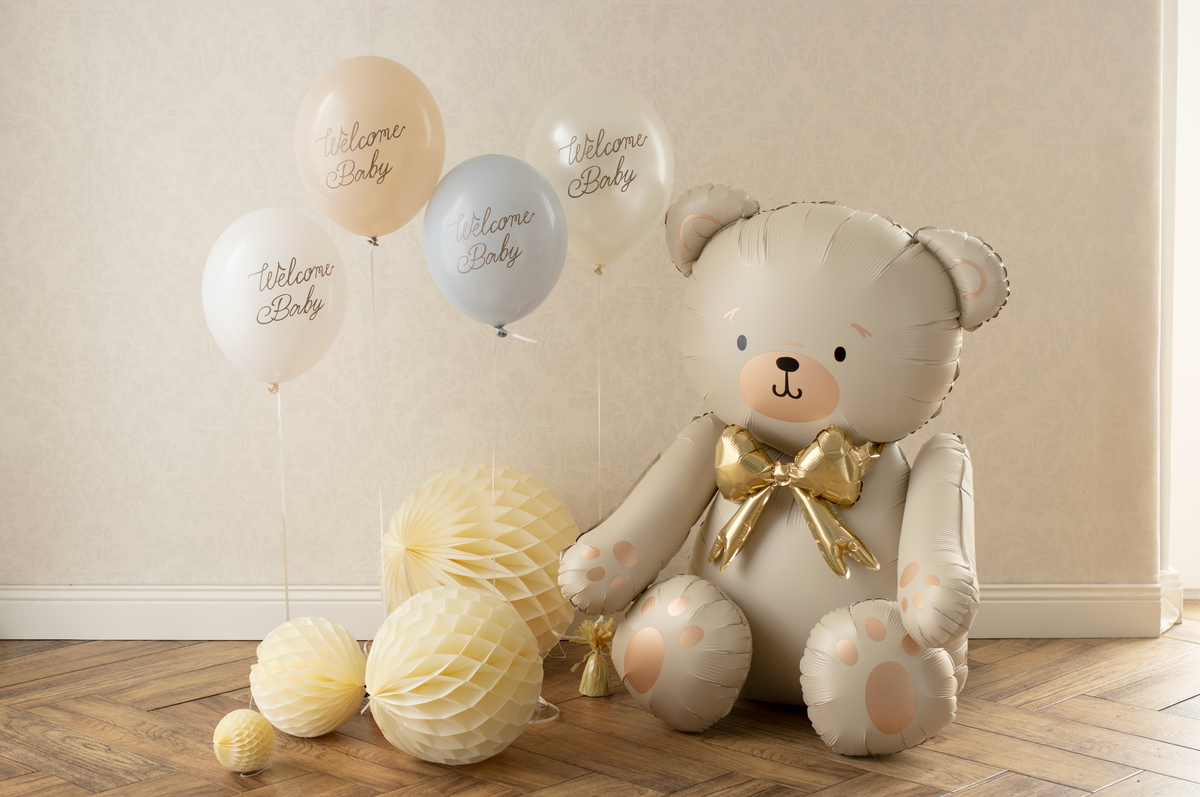 Teddy bear with balloons on a wooden floor against a beige wall