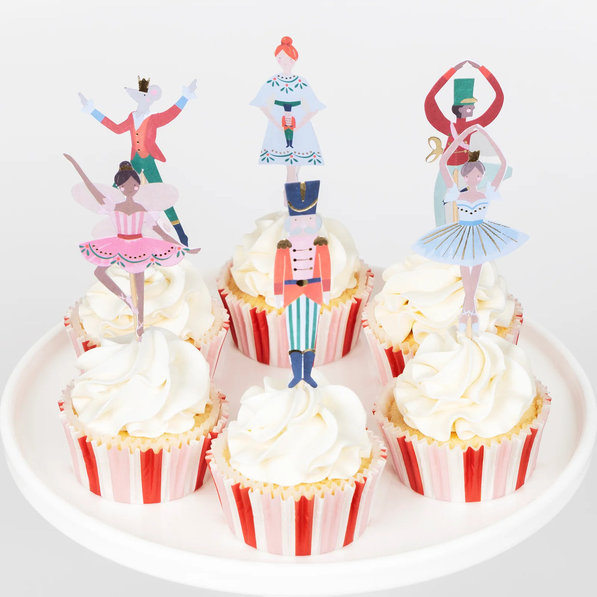 Cupcakes with decorative Nutcracker-themed toppers on a white plate.