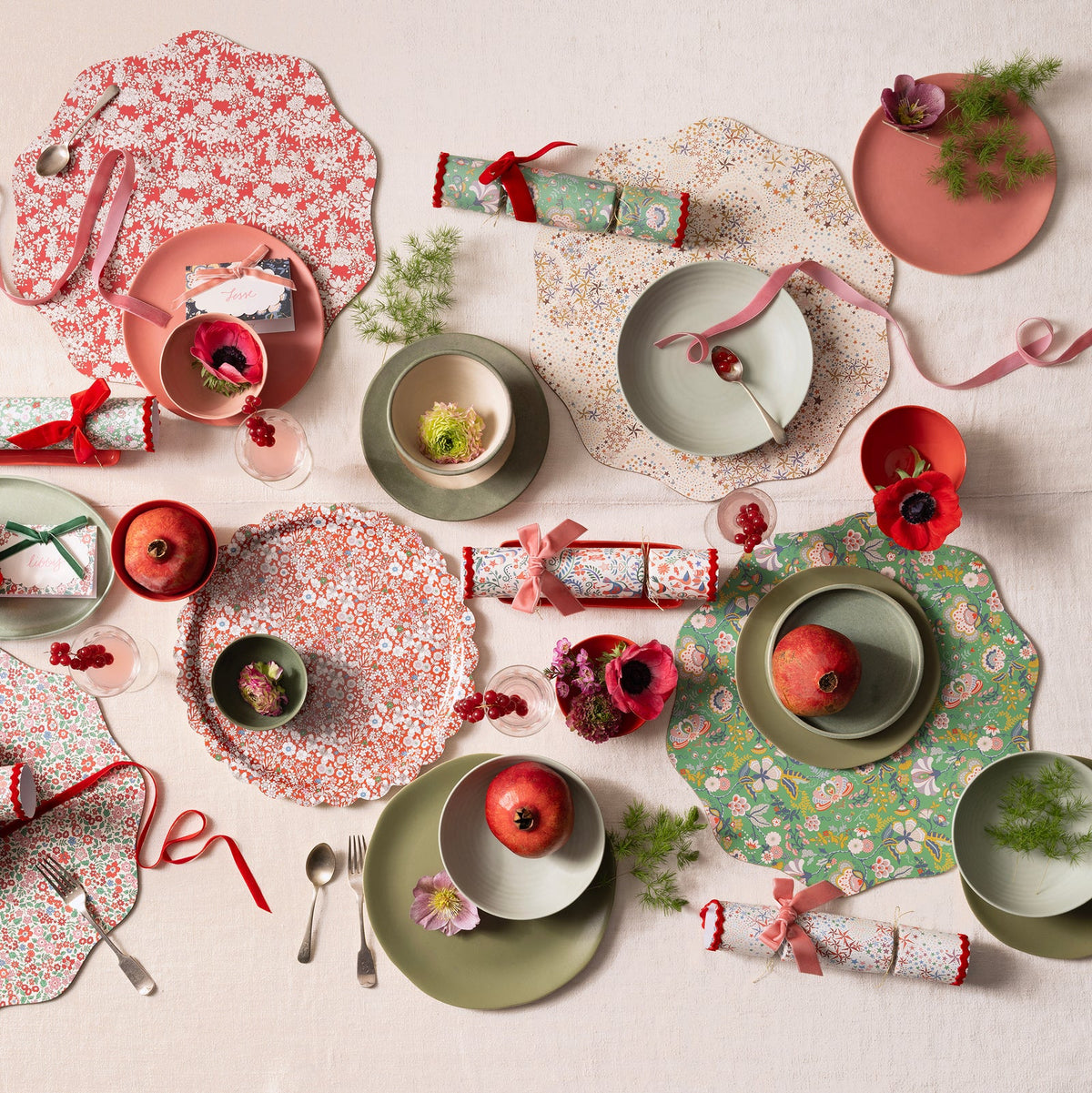 Decorative table setting with floral plates, pomegranates, and crackers on a light background