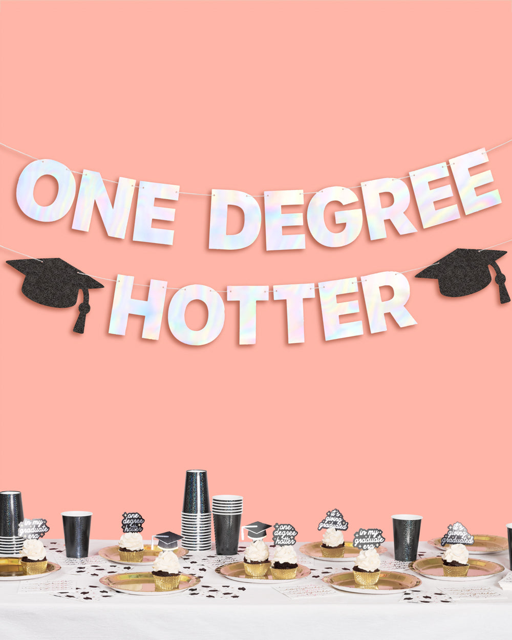 Graduation-themed party setup with &#39;ONE DEGREE HOTTER&#39; banner on a pink background