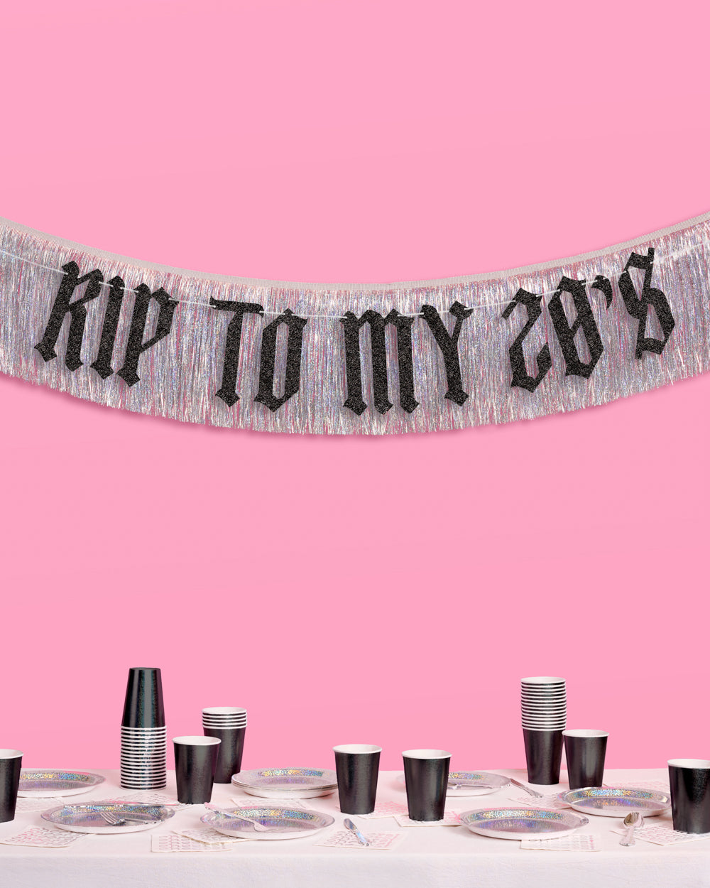 Decorative banner with 'Kiss to my 28's' text on a pink background, with a table set for a party below.