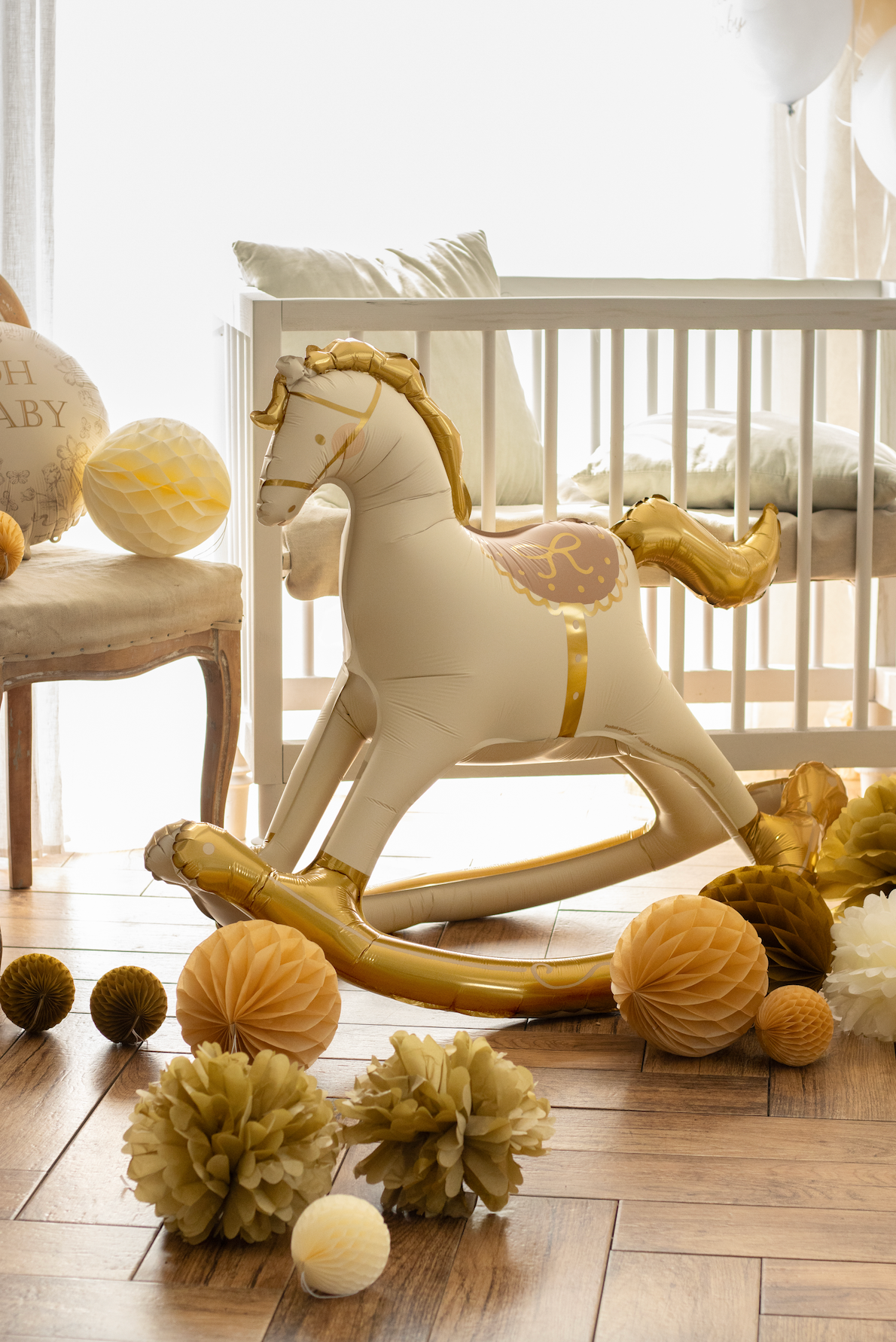 White and gold rocking horse toy on a wooden floor with decorative items