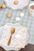 Decorative table setting with a teacup, cookies, and a spoon on a checkered tablecloth.
