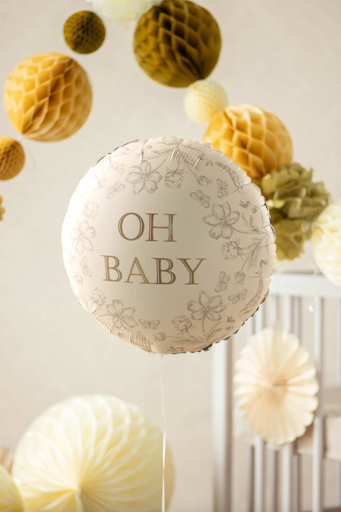 Decorative balloon with &#39;OH BABY&#39; text in a baby shower setting with paper flowers.