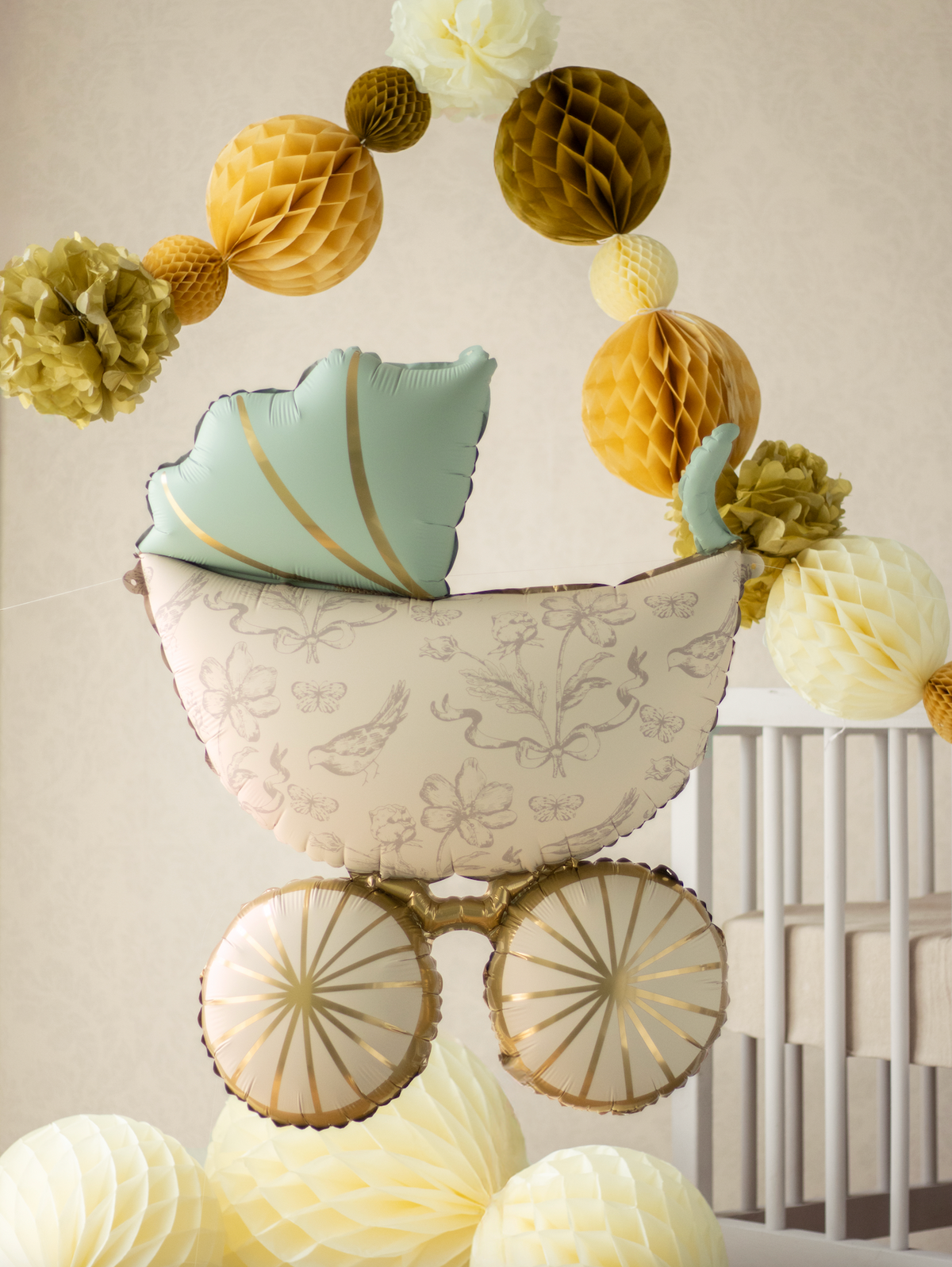 Decorative baby shower cradle with paper flowers and balloons against a neutral background