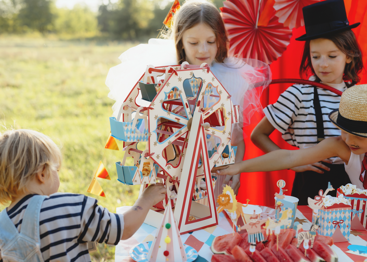 Children playing with a carnival-themed paper craft outdoors.