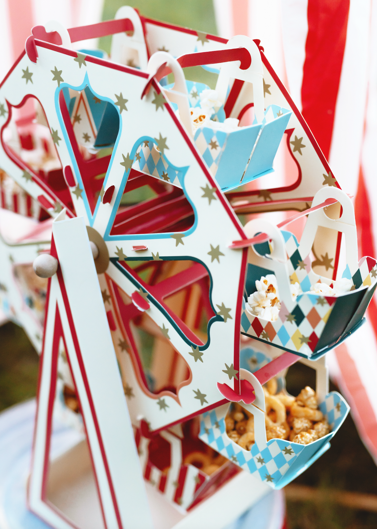 Ferris wheel-shaped candy holder with popcorn and candy on a white background