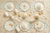 Decorative plates and cups with whipped cream and small pastries on a textured beige background
