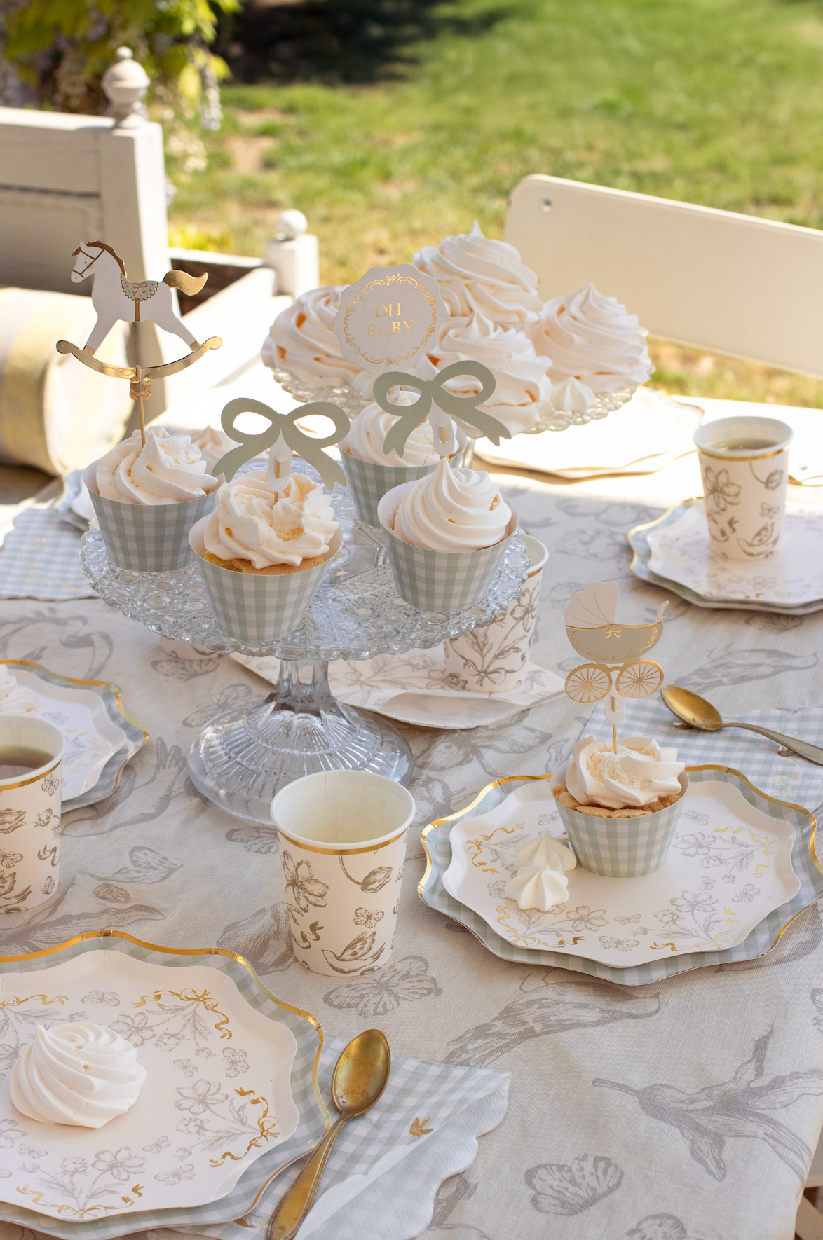 Table setting with decorative items, including a floral centerpiece and teacups, on a patterned tablecloth.