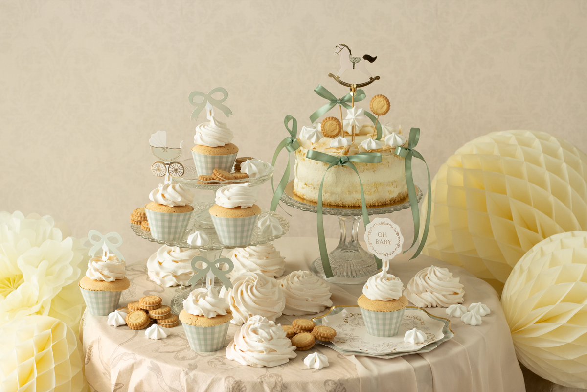 Decorative dessert table with cupcakes, cookies, and a cake on a light background