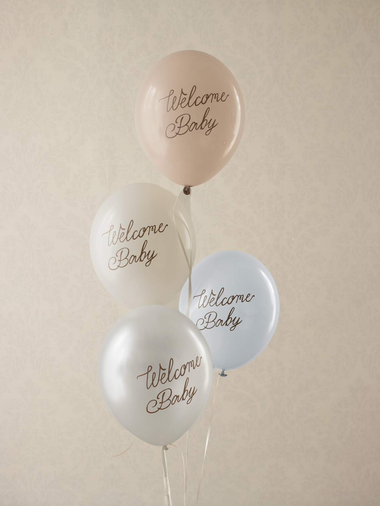 White balloons with 'Welcome Baby' text in gold on a white background