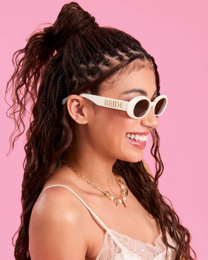 Woman wearing sunglasses with &#39;Bride&#39; text on a pink background