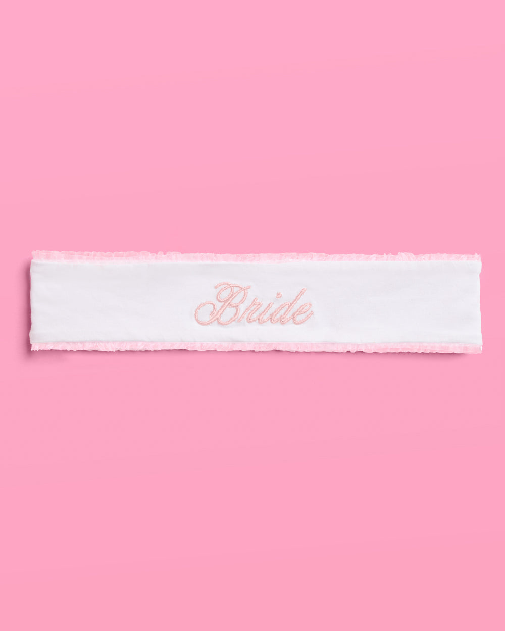 White headband with &#39;Bride&#39; embroidery on a pink background
