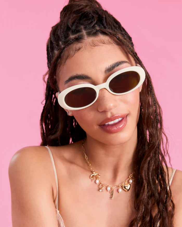 Woman wearing white sunglasses with a pink background