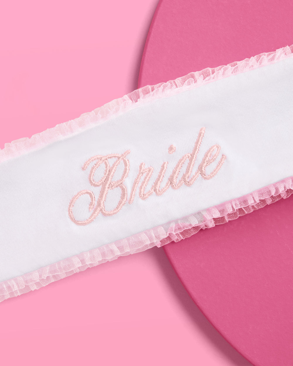 White sash with &#39;Bride&#39; embroidery on a pink background