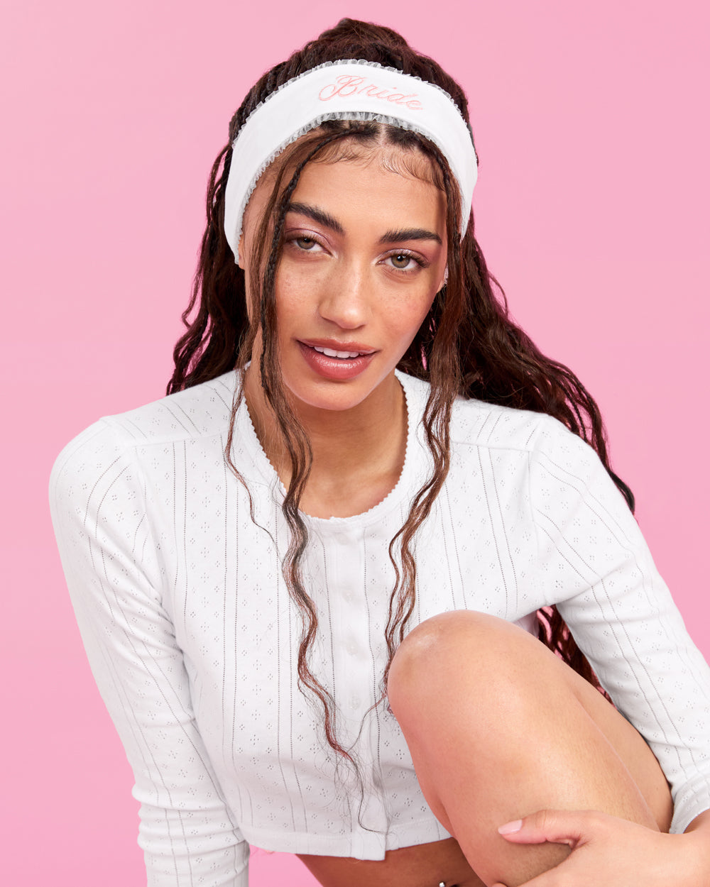 Woman wearing a white headband with text on a pink background