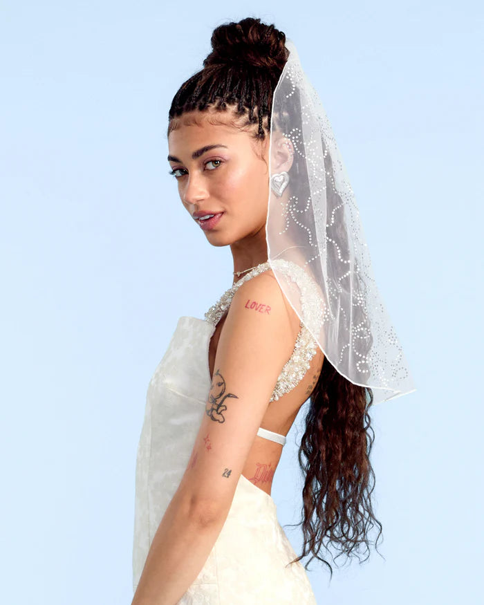 Woman wearing a white wedding dress with a veil against a light blue background