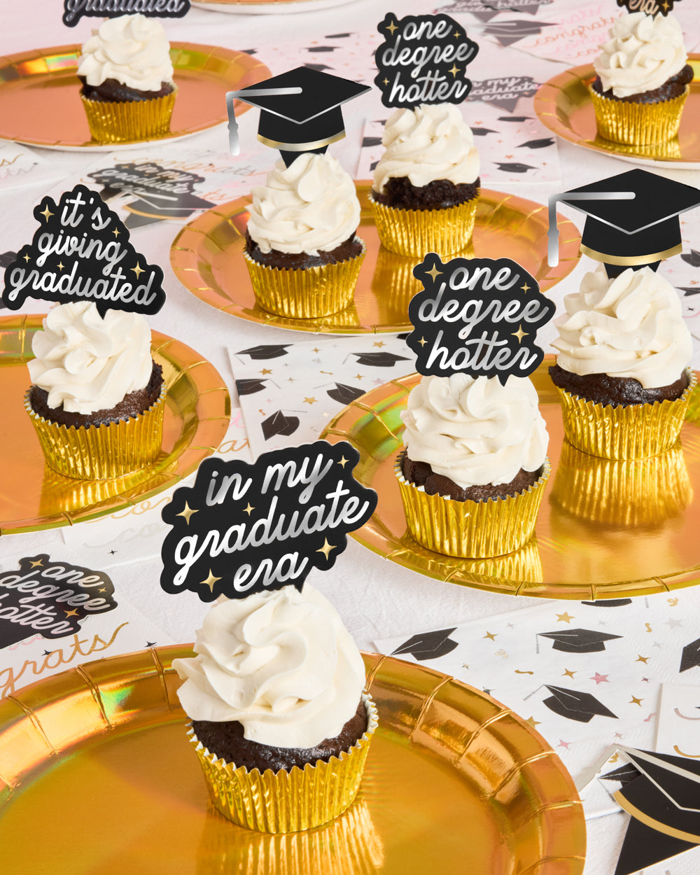 Graduation-themed cupcakes with decorative toppers on a table setting.
